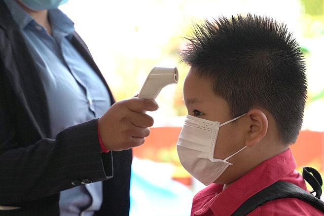 A student from the Sovannaphumi school wearing a face mask has his temperature checked as Cambodia reopen schools and museums after months of shutdown due to surging of the coronavirus disease (COVID-19) in Phnom Penh, Cambodia, January 4, 2021. (Photo by Cindy Liu/Reuters)