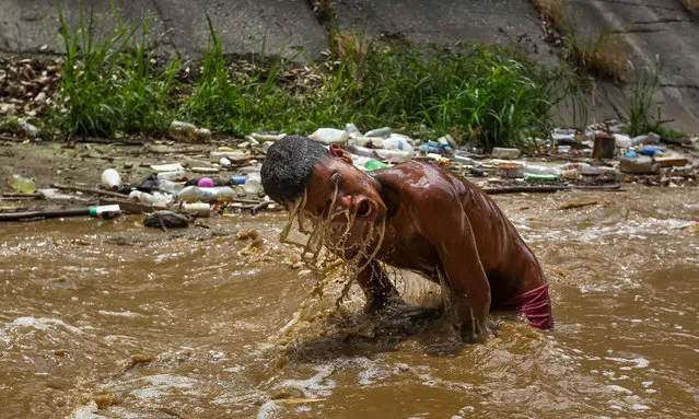 Ronaldo, 19, searches for valuable objects in the Guaire River in Caracas, Venezuela, 13 May 2019. Because of the crisis, hundreds of youngsters gather every day in the river, used to dump sewage water and industrial waste, in order to rescue valuable objects they can later sell. According to these young 'miners', if they can manage to find any gold object, such as an earring, collar or ring, they can sell each gram of gold for in between 130,000 and 200,000 Venezuelan bolivars (roughly between 23 and 35 US dollar depending on the currency's devaluation), although silver and bronze are also worth selling. (Photo by Raul Martinez/EPA/EFE)