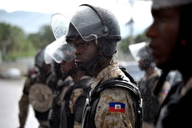 Haitian National Police stand guard in front of the Haitian Parliament during a protest of supporters of PHTK political party in Port-au-Prince, on May 3, 2016. Supporters of PHTK political party marched to the facilities of the Haitian Parliament to demand that the second round of presidential elections are held. (Photo by Hector Retamal/AFP Photo)
