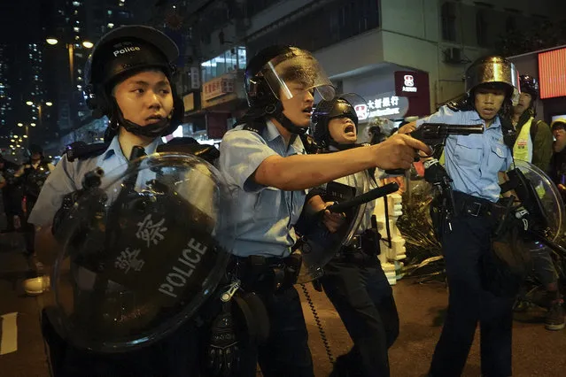 Policemen pull out their guns after a confrontation with demonstrators during a protest in Hong Kong, Sunday, August 25, 2019. Hong Kong police have rolled out water cannon trucks for the first time in this summer's pro-democracy protests. The two trucks moved forward with riot officers Sunday evening as they pushed protesters back along a street in the outlying Tsuen Wan district. (Photo by Vincent Yu/AP Photo)