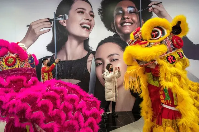 A woman takes photos as traditional Lion dance performers dance during a show for the Chinese Lunar New Year and Spring Festival holiday at a shopping mall on February 7, 2022 in Beijing, China. The dances are still an important part of Chinese culture, and while still popular today were traditionally believed to ward off evil spirits and bring good luck and prosperity.China is celebrating the Lunar New Year and Spring Festival holiday which began on February 1st. (Photo by Kevin Frayer/Getty Images)