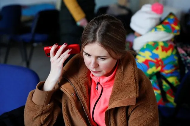 A woman from Ukraine listens to Ukrainian President Volodymyr Zelenskiy's speach on a phone,  at a refugee shelter after Russia's invasion of Ukraine, in Beregsurany, Hungary, February 28, 2022. (Photo by Bernadett Szabo/Reuters)