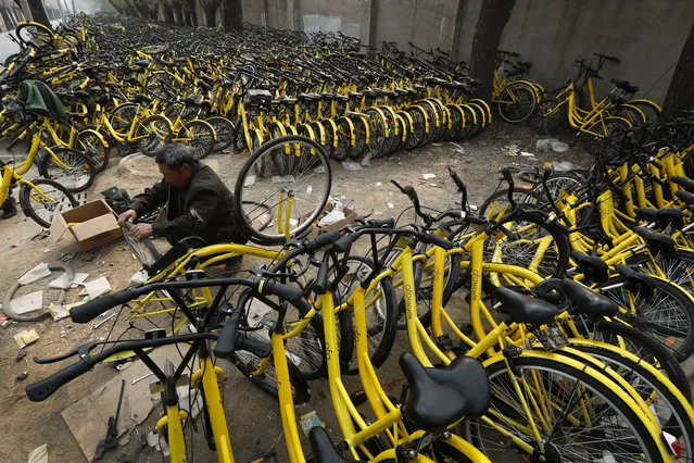 In this Sunday, March 19, 2017 photo, a worker fixes a bicycle's tyre at the repair station for the bike-sharing company Ofo in Beijing, China. (Photo by Andy Wong/AP Photo)