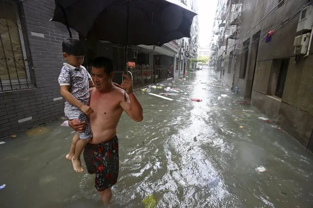 A man holds his grandson as he walks along a flooded street amid heavy rainfall under the influence of Typhoon Chan-hom, in Ningbo, Zhejiang province, China, July 11, 2015. (Photo by Reuters/Stringer)