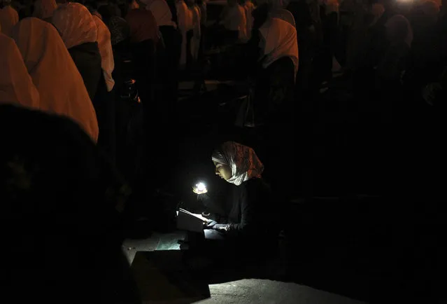 A woman uses her mobile phone to illuminate the Koran as supporters of the Jordanian opposition and Syrians living in Jordan perform prayers during the holy month of Ramadan before a protest in front of the Syrian Embassy in Amman August 2, 2011. (Photo by Muhammad Hamed/Reuters)