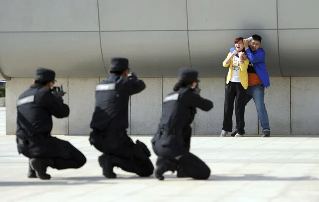 Police officers take aim with their weapons at a man playing the role of an attacker as he holds a woman hostage during an anti-terrorism drill at a railway station in Zhengzhou May 10, 2014. An assailant stabbed six people on Tuesday at a railway station in the southern Chinese city of Guangzhou, police and state media said, the latest in a series of attacks that have unnerved the country, some of which Beijing has termed terrorism. (Photo by Reuters/Stringer)