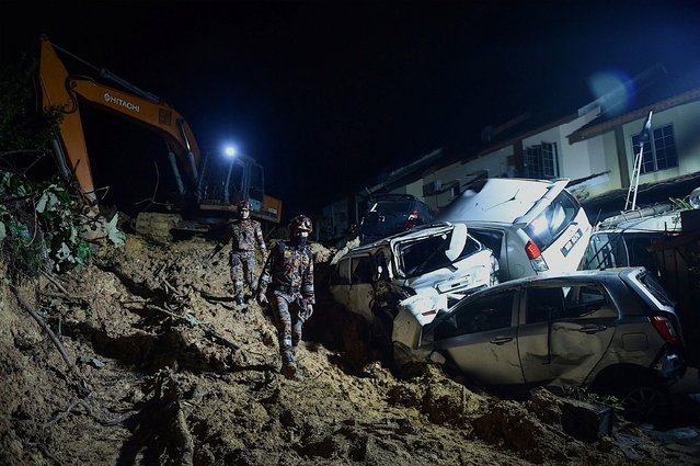 Rescue workers search for victims after a landslide was triggered by heavy rains in the township of Ampang, outside Kuala Lumpur early on March 11, 2022. (Photo by Arif Kartono/AFP Photo)