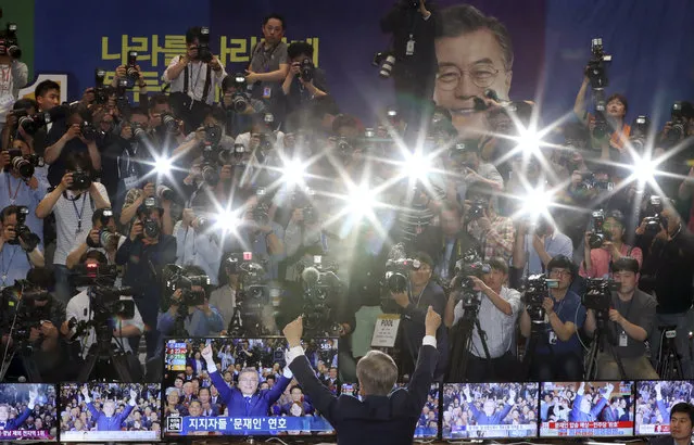 South Korea's presidential candidate Moon Jae-in of the Democratic Party raises his hands in front of the media as his party leaders, members and supporters watch on television local media's results of exit polls for the presidential election at National Assembly in Seoul, South Korea, Tuesday, May 9, 2017. Exit polls forecast that liberal candidate Moon win the election Tuesday to succeed ousted President Park Geun-hye. (Photo by Lee Jin-man/AP Photo)