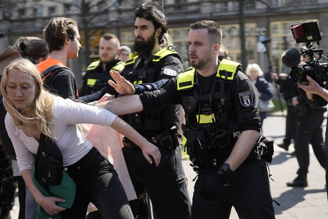 A police officer pushes a protestor away as police try to stop a march by activists of the “Letzte Generation”, Last Generation, against the climate policy of the German government in central in Berlin, Germany, Friday, April 21, 2023. (Photo by Markus Schreiber/AP Photo)