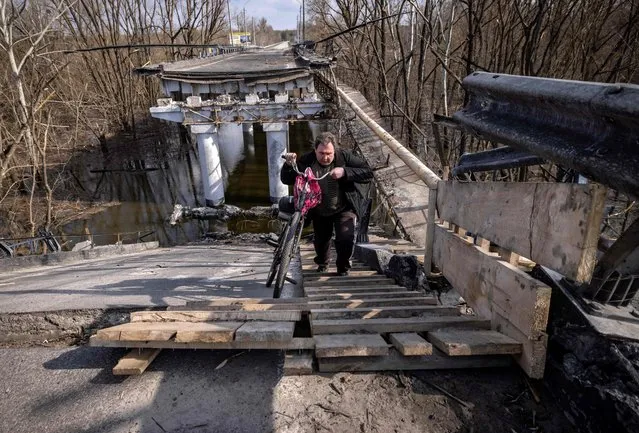 A man crosses a destroyed bridge near the village of Bohorodychne in the Donbass region on April 5, 2022. (Photo by Fadel Senna/AFP Photo)