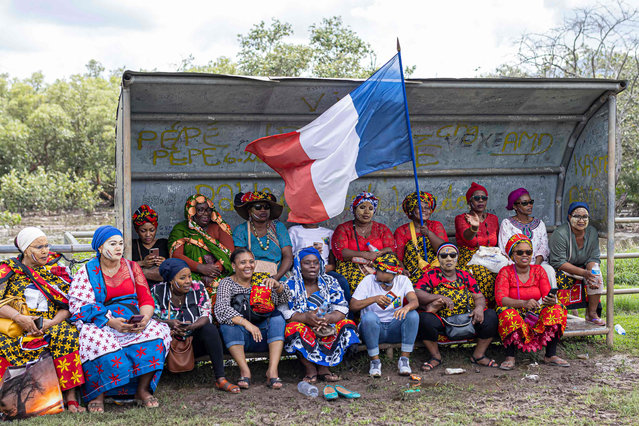 A woman holds a French flag as she and others listen to a speech during a rally in support of Operation Wuambushu (“Take Back”) in Chirongui, on the island of Mayotte, on April 27, 2023. Authorities in Mayotte were expected to launch Operation Wuambushu as early as this weekend to remove illegal migrants who have settled in slums on the island, with more than 2,000 police and administrative officials mobilised to set in train the expulsions of those illegally on the island and tear down the makeshift squats housing them. (Photo by Patrick Meinhardt/AFP Photo)