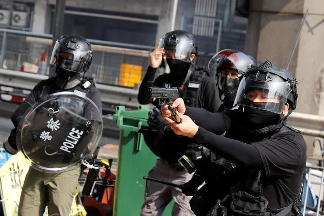 A riot police officer points a gun at protesters attempting to escape the campus of Hong Kong Polytechnic University (PolyU) during clashes with police in Hong Kong, China on November 18, 2019. (Photo by Thomas Peter/Reuters)