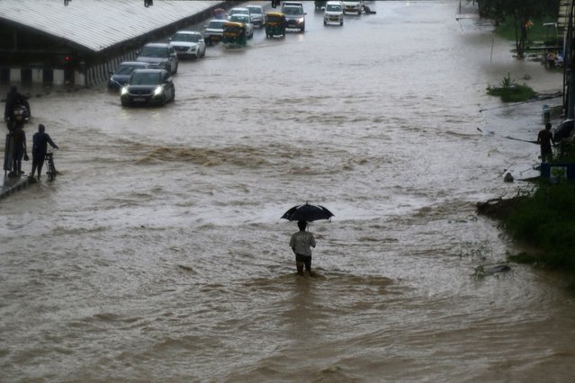 People commute through a waterlogged road after heavy rainfall in Gurgaon on August 11, 2024. (Photo by Vinay Gupta/AFP Photo)