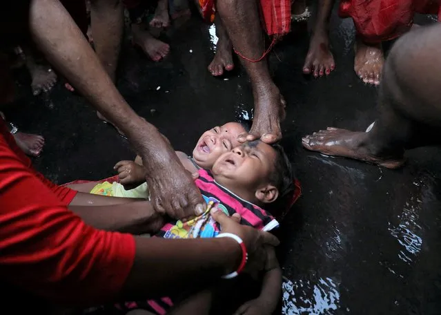 Hindu devotees touch infants with their feet as part of a ritual to bless them during a religious procession held to mark the Gajan festival in Kolkata, India, April 13, 2022. (Photo by Rupak De Chowdhuri/Reuters)