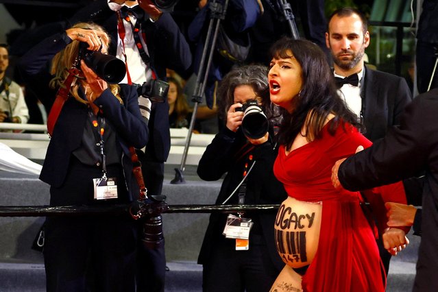 A woman wearing a prop pregnant belly reading “Surrogacy” and a drawn barcode is detained by security as she protests on the red carpet ahead of the screening of the film “Le Retour” (Homecoming) during the 76th edition of the Cannes Film Festival in Cannes, southern France, on May 17, 2023. (Photo by Eric Gaillard/Reuters)