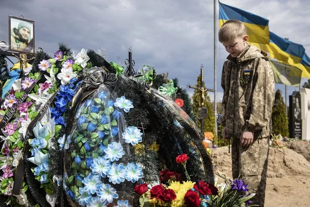 Ten-year-old Savelii reacts at his father's grave, who died defending Irpin city as a member of territorial defense, in Irpin, Ukraine, 01 May 2022. Russian troops entered Ukraine on 24 February resulting in fighting and destruction in the country and triggering a series of severe economic sanctions on Russia by Western countries. (Photo by Mikhail Palinchak/EPA/EFE)