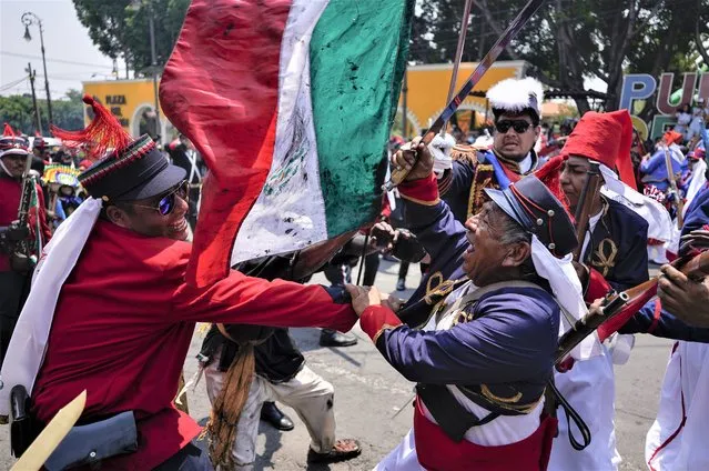 People dressed as Zacapoaxtla Indigenous people clash with others playing the part of French soldiers as they reenact The Battle of Puebla as part of Cinco de Mayo celebrations in the Peñon de los Baños neighborhood of Mexico City, Thursday, May 5, 2022. Cinco de Mayo commemorates the victory of an ill-equipped Mexican army over French troops in Puebla on May 5, 1862. (Photo by Eduardo Verdugo/AP Photo)