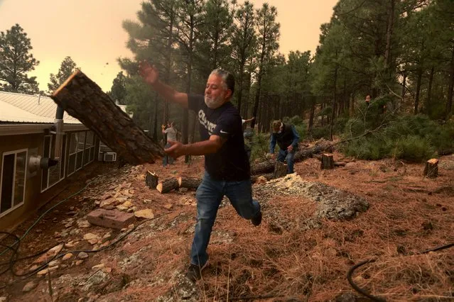 Chris Castillo throws a freshly cut log as he and his cousins clear a wireline along a family member’s home a family in Las Vegas, NM on Monday, May 2, 2022. Wind-whipped flames are marching across more of New Mexico’s tinder-dry mountainsides, forcing the evacuation of area residents and dozens of patients from the state's psychiatric hospital as firefighters scramble to keep new wildfires from growing. (Photo by Cedar Attanasio/AP Photo)