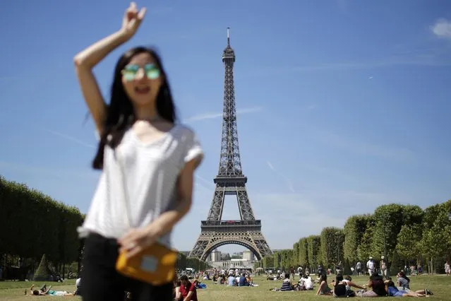 A tourist poses for a photo souvenir in front of the Eiffel Tower in Paris, France, August 2, 2015 as warm summer temperatures return to the French capital. (Photo by Stephane Mahe/Reuters)