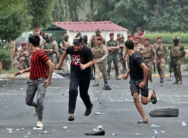 Iraqi security forces chase anti-government protesters in Baghdad, Iraq, Sunday, October 6, 2019. The protests began with demands for jobs and an end to corruption, and now include calls for justice for those killed in the protests. (Photo by Hadi Mizban/AP Photo)