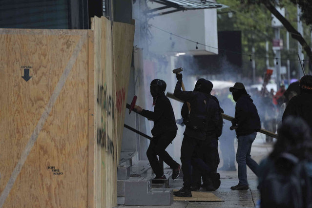 Masked youths destroy a barrier protecting the facade of a building during a march marking the 10-year anniversary of the disappearance of 43 students from an Ayotzinapa rural teacher's college, in Mexico City, Thursday, September 26, 2024. (Photo by Fernando Llano/AP Photo)