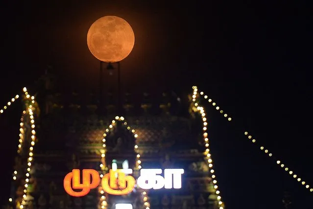 Full moon is pictured next to the illuminated Kapaleeswarar temple on occasion of Vaikasi Visagam celebration in Chennai on June 14, 2022. (Photo by Arun Sankar/AFP Photo)