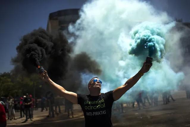 A man holds smoke bombs during a protest by Spanish taxi drivers unions in Madrid, Thursday, July 27, 2017. Taxi drivers unions called for a 24-hours strike to protest the increase in cars run by private companies offering cheaper, mobile ride-hailing services. (Photo by Francisco Seco/AP Photo)