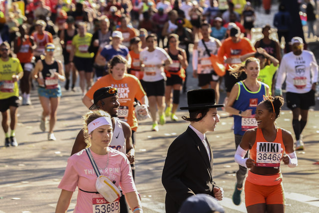 An orthodox Jewish man crosses the street through as New York City Marathon runners pass through Brooklyn, Sunday, November 3, 2024, in New York. (Photo by Heather Khalifa/AP Photo)