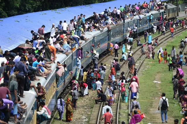 Bangladeshis wait at a train station to board packed trains as they rush home to their respective villages to be with their families ahead of the Muslim festival of Eid al-Fitr, in Dhaka on July 28, 2014. The Eid al-Fitr, the biggest festive Muslim event, marks the end of the holy fasting month of Ramadan. (Photo by Munir Uz Zaman/AFP Photo)