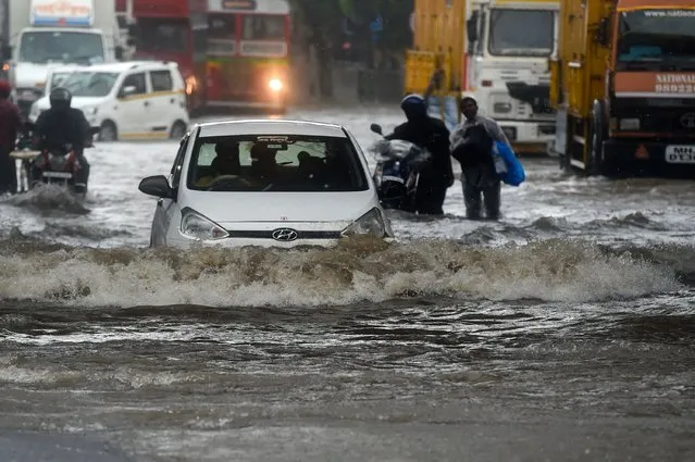 Vehicles drive through flooded street during rain showers in Mumbai on July 5, 2022. (Photo by Punit Paranjpe/AFP Photo)