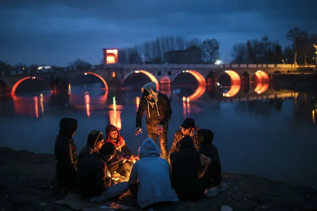 Migrants sit around a fire in Edirne near the Turkish-Greek border on Thursday, March 5, 2020. Turkey said Thursday it would deploy special forces along its land border with Greece to prevent Greek authorities from pushing back migrants trying to cross into Europe, after Turkey declared its previously guarded gateways to Europe open. (Photo by Emrah Gurel/AP Photo)