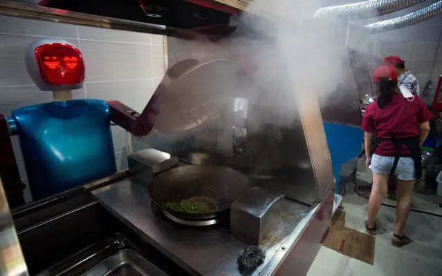 This photo taken on August 13, 2014, shows a robot “cooking” vegetables in a kitchen of a restaurant in Kunshan. (Photo by Johannes Eisele/AFP Photo)