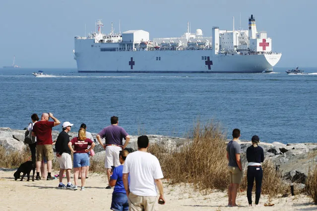 Local residents watch as the USNS Comfort departs Hampton Roads en route to New York to help in the response to the coronavirus outbreak Saturday, March 28, 2020, in Hampton, Va. (Photo by Steve Helber/AP Photo)