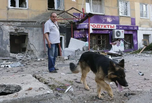 A man with a dog stands in front of a building damaged by, what locals say, was recent shelling by Ukrainian forces, in Donetsk, August 20, 2014. (Photo by Maxim Shemetov/Reuters)