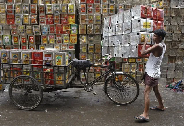A man loads empty containers of edible oil onto a tricycle at a roadside in Kolkata, India, August 27, 2015. (Photo by Rupak De Chowdhuri/Reuters)