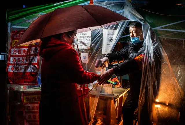 This photo taken on April 20, 2020 shows a staff member (R) checking the body temperature of a resident before she enters a community in Mudanjiang in China's northeastern Heilongjiang province. (Photo by AFP Photo/China Stringer Network)