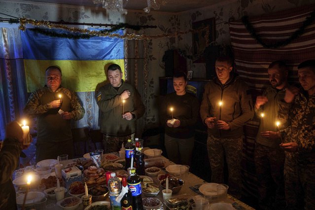 Ukrainian servicemen of 117th Separate Heavy Mechanized Brigade pray before a Christmas dinner on Pokrovsk direction, Donetsk region, Ukraine, December 24, 2024. (Photo by Evgeniy Maloletka/AP Photo)