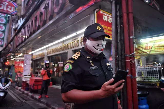 A policeman in a mask, as a preventive measure against the spread of the COVID-19 coronavirus, patrols Chinatown in Bangkok on April 17, 2020. (Photo by Lillian Suwanrumpha/AFP Photo)