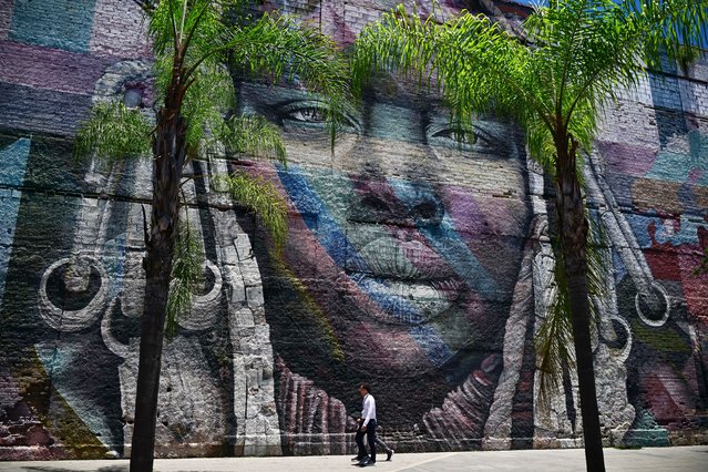 People walk past grafitti made by Brazilian artist Kobra at the port zone of Rio de Janeiro, Brazil, on November 6, 2024. The G20 Social Summit will take place at the port zone of Rio de Janeiro between November 14 and 16, 2024, on the eve of the G20 Leaders' Summit. (Photo by Mauro Pimentel/AFP Photo)