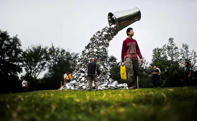 Visitors look at the sculpture “Ray” created by Indian artist Subodh Gupta as part of the Jing'An International Sculpture Project Biennial at a park in Shanghai, China, on October 5, 2012. (Photo by Eugene Hoshiko/Associated Press)