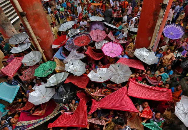 Hindu devotees hold up clothes and umbrellas to receive rice as offerings being distributed by a temple authority on the occasion of the Annakut festival in Kolkata, India October 20, 2017. (Photo by Rupak De Chowdhuri/Reuters)