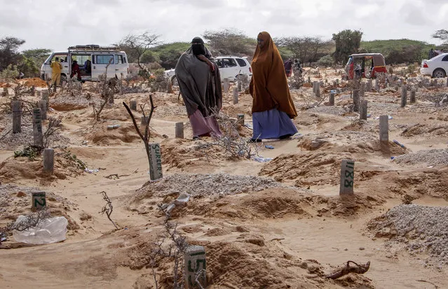 In this photo taken Wednesday, May, 13, 2020, women walk past graves at a cemetery in Mogadishu, Somalia, following the burial of a man who died of coronavirus. Years of conflict, instability and poverty have left Somalia ill-equipped to handle a health crisis like the coronavirus pandemic. It’s uncertain how many cases of COVID-19 are in Somalia. (Photo by Farah Abdi Warsameh/AP Photo)