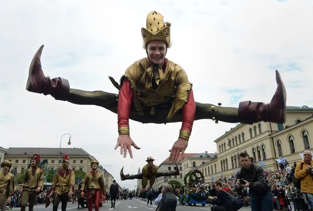 An impostor jumps during the traditional costume parade of the Bavarian Oktoberfest festival in in the city of Munich, southern Germany, on September 21, 2014. Germany's world-famous Oktoberfest kicks off with millions of revellers set to soak up the frothy atmosphere in a 16-day extravaganza of lederhosen, oompah music and beer. (Photo by Christof Stache/AFP Photo)