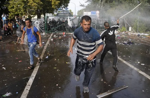 Migrants run as Hungarian riot police fires tear gas and water cannon at the border crossing with Serbia in Roszke, Hungary September 16, 2015. Hungarian police fired tear gas and water cannon at protesting migrants demanding they be allowed to enter from Serbia on Wednesday on the second day of a border crackdown. (Photo by Marko Djurica/Reuters)