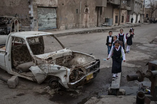 Children walk to school past destroyed cars in West Mosul on November 6, 2017 in Mosul, Iraq. (Photo by Chris McGrath/Getty Images)