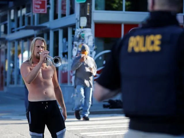 A protester plays a trumpet in front of a Seattle Police Officer at the CHOP area (Capitol Hill Occupied Protest), as people continue to occupy space and protest against racial inequality in the aftermath of the death in Minneapolis police custody of George Floyd, in Seattle, Washington, U.S. June 26, 2020. (Photo by Lindsey Wasson/Reuters)
