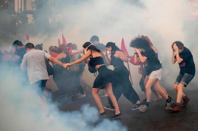 Protesters run amid tear-gas smoke during clashes with riot police during a demonstration outside the Greek parliament against a new law on protest rules in Athens, on July 9, 2020. (Photo by Angelos Tzortzinis/AFP Photo)