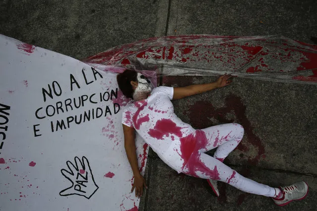 A protestor stained with fake blood lies beside a sheet marked with slogans protesting corruption and impunity as well as government repression, outside the offices of congress in Mexico City, Thursday, September 1, 2016. When President Enrique Pena Nieto delivers his annual report to congress on Thursday, he'll reflect on a year that has seen rising homicide rates, a sluggish economy and a midterm electoral rout of his party. His administration has also been stung by a string of scandals as well as reports of alleged torture and human rights abuses by police and troops. (Photo by Rebecca Blackwell/AP Photo)