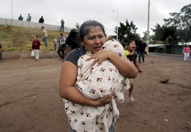 A woman carries a baby affected by tear gas near a barricade erected by supporters of presidential candidate Salvador Nasralla protesting official election results in Tegucigalpa, Honduras, Monday, December 18, 2017. President Juan Orlando Hernandez has been declared the winner of Honduras' disputed election, but that isn't quelling unrest from weeks of uncertainty as his main challenger calls for more protests Monday and vows to take his claims of fraud to the OAS. (Photo by Fernando Antonio/AP Photo)