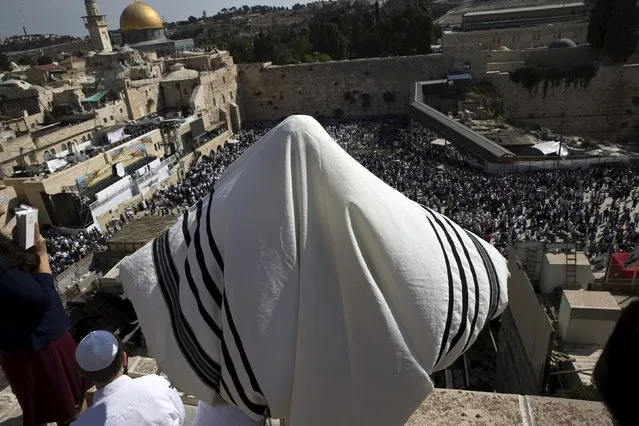 A Jewish worshipper covers himself in a prayer shawl as he recites the priestly blessing while over looking the Western Wall in Jerusalem's Old City during the holiday of Sukkot September 30, 2015. (Photo by Ronen Zvulun/Reuters)